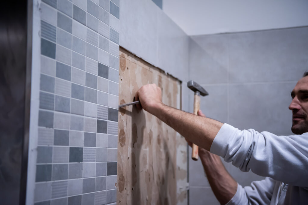 worker demolishing old tiles in a bathroom
